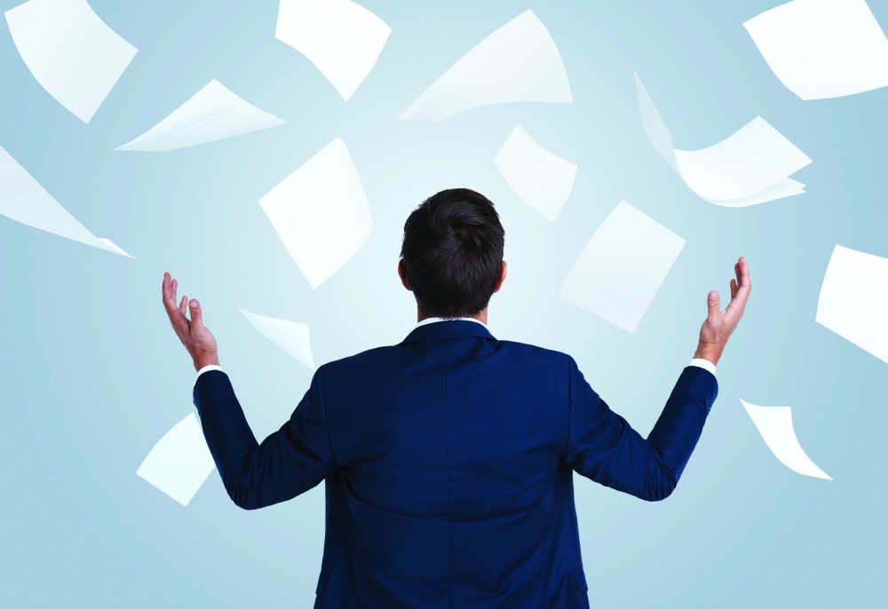 Rearview studio shot of a young businessman overwhelmed by paperwork